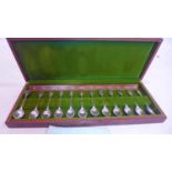 A teak-cased presentation box containing 12 sterling silver and 24ct yellow gold tea spoons, L: 12.