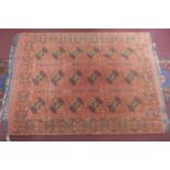 A Pakistani Turkoman hand-made woolen carpet, elephant pad motifs on a rouge field, within geometric