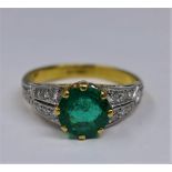 An 18ct yellow and white gold diamond and emerald ring, centrally set to the centre with a round