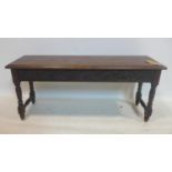 A 19th century oak bench, with floral carving to side panels, raised on turned supports and