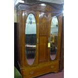 An early 20th century mahogany wardrobe, the arched pediment above two cupboard doors having