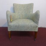 An early 20th century armchair, with floral upholstery, on tapered legs and castors, H.76cm