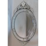 A Venetian style glass mirror, with etched floral design and floral finial, having oval bevelled