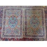 A pair of early 20th century central Persian Kirman rugs, with floral medallion surrounded by floral