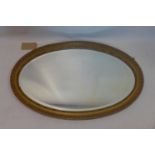 A late 19th/early 20th century oval gilt wood mirror with bevelled plate, 94 x 58cm