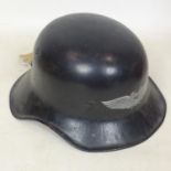 A reproduction WWII black-painted steel German helmet, with printed silver winged motif to back
