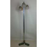 An Art Deco cast metal floor standing lamp, with three branches having stepped domed glass shades,