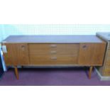 A 20th century teak sideboard with three central drawers, flanked by 2 sliding doors, raised on