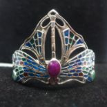 A sterling silver, plique a jour enamel dragonfly bangle set with a ruby, two emeralds and two