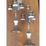A pair of brass and alabaster candle sticks each with three sconces on circular bases, H: 39cm
