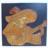 A 1970's leather artwork on panel depicting a gentleman in hat playing classical guitar, 59 x 61cm