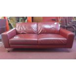 A contemporary red leather sofa raised on chrome feet