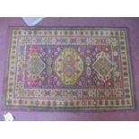 A Persian style woollen rug, three medallions on a purple and rouge ground, within floral