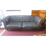 A grey leather Chesterfield sofa raised on turned legs