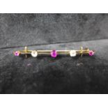 A 19th century, 18ct yellow gold bar brooch alternately set with three faceted rubies and two