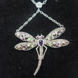 A sterling silver dragonfly necklace set with an amethyst cabochon body, ruby eyes, marcasites and