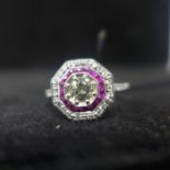 An 18ct white gold diamond and ruby cluster ring in the Art Deco style, the round central diamond (