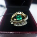 A boxed 14ct yellow and white gold ring centrally set with a feceted sqaure emerald flanked by two
