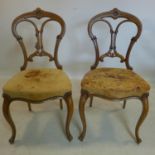 A pair of Victorian carved walnut chairs, with studded leather seats, raised on cabriole legs
