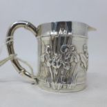A Chinese white metal milk jug, with bamboo design handle, decorated with pond flowers, signed, H.