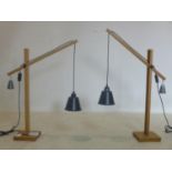 A pair of contemporary beech wood angle poise table lamps, with hanging black shades and counter