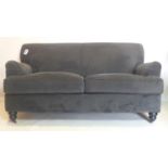 A contemporary grey velour upholstered sofa, raised on turned legs and castors