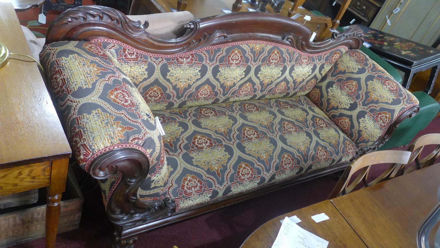 A Victorian carved mahogany sofa raised on turned legs and castors