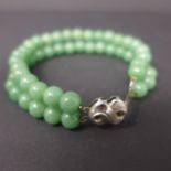 A Chinese, silver and polished green jade bead bracelet of 2 rows, L: 16cm, 23.5g