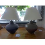 A pair of earthenware table lamps, with incised geometric decoration, having cream shades, H.59cm