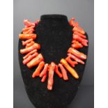 A silver clasped, natural coral necklace composed of 34 long coral beads, L: 50cm, 320g