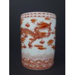 A 20th century Chinese cylindrical porcelain brush pot, decorated in iron red with dragons chasing