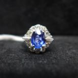 An 18ct white gold diamond and sapphire cluster ring, centrally set with a large faceted sapphire (