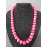 A natural faceted ruby necklace composed of 38 graduated beads to a silk tie thong fastening, L.