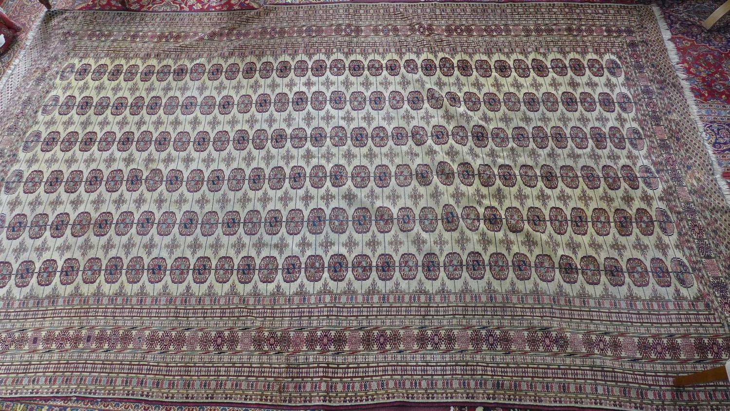 A large 20th century Caucasian Bokhara carpet with repeating gull motifs, on a beige ground,