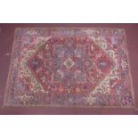 An antique Heriz carpet with geometric medallion on a red ground, contained by geometric borders,