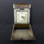 A silver and leather travel clock, the square dial with Arabic numerals and marked Facille,