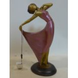An Art Deco style cast plaster figure of a dancing lady in a pink dress, on stepped oval base, H.