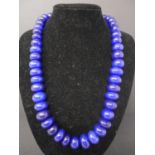 A natural polished sapphire necklace composed of 45 graduated beads to a silk tie thong fastening,