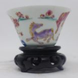 A 19th century Chinese tea cup/bowl, decorated with horses frolicking in a field, on wooden stand,
