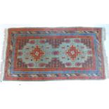A Persian rug with geometric designs, on a red and blue ground, 180 x 95cm
