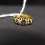 An Edwardian, 18ct yellow gold ring set with alternating sapphire and diamonds to a carved mount,