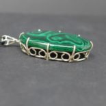 A sterling silver pendant set with a large, oval, polished malachite cabochon to a silver pendant