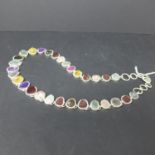 A silver necklace set with raw gemstones in collet mounts to include aquamarine, amethyst,
