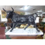 A large cast iron, black-painted bull sculpture secured to a rectangular white marble plinth base,