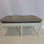 A 20th century white painted window stool, with floral upholstered seat, on reeded legs, H.54 W.