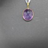 A 14ct yellow gold pendant set with an oval checker-board faceted natural amethyst to a yellow