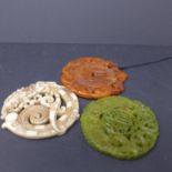 Three Chinese hard stone and hand carved amulets/pendants in shades of green, white and orange,