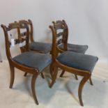 A set of four Regency mahogany dining chairs, with carved back rests and brass inlay, raised on