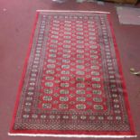 A Persian Bokhara rug, with elephant pad motifs on a rouge field, within border with floral