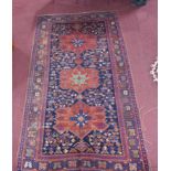 An antique Kazakh carpet with 3 geometric medallions, surrounded by geometric motifs on a blue